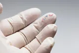 white gloved hand with microplastic fragments
