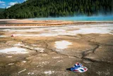 a red, white, and blue bucket hat in the Grand Prismatic Spring in Yellowstone 