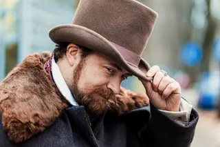 Man tipping his hat as a gesture of politeness, reflecting social etiquette and the historical meaning of hat-wearing in Western culture.