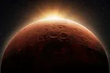 Mars in space with the sun rising behind it 