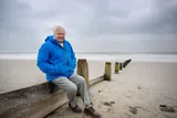 Sir David Attenborough sitting near a beach for the film Ocean with David Attenborough 