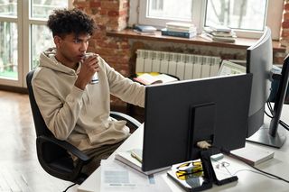 young person drinking an energy drink sitting at a computer 