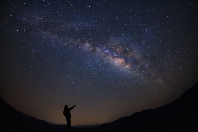 Person standing and stargazing up at the night sky