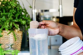 person scooping protein powder into a shake