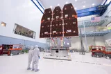 Two technicians in protective gear looking at the Nancy Grace Roman Space Telescope 