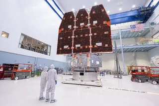 Two technicians in protective gear looking at the Nancy Grace Roman Space Telescope 