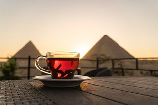 Drinking hot tea outside, with Egyptian pyramids in the background