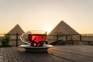 Drinking hot tea outside, with Egyptian pyramids in the background