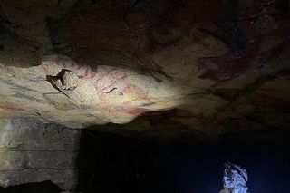 Researchers looking at red pigment on cave ceiling 
