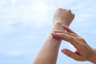 Person applying sun screen to avoid skin allergy from the sun