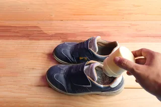 someone sprinkling odor remover in smelly shoes