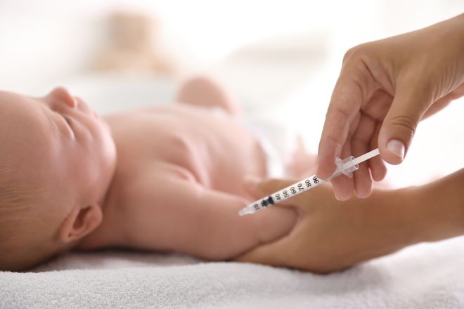 A doctor giving a newborn baby a vaccine needle