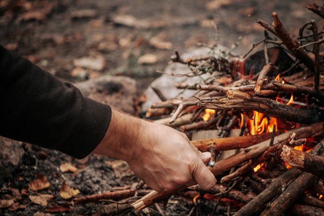 person putting sticks on a fire