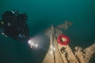 Diver places a wreath on the tiller of HMS Tiger