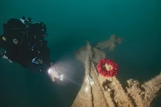 Diver places a wreath on the tiller of HMS Tiger