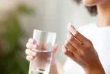 woman taking a pill with a glass of water 