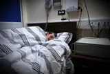 A participant sleeps in a bed with EEG sensors attached to their scalp during a brain and memory study.