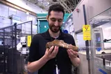 man holding fossilized dinosaur rib 