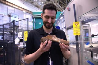 man holding fossilized dinosaur rib 