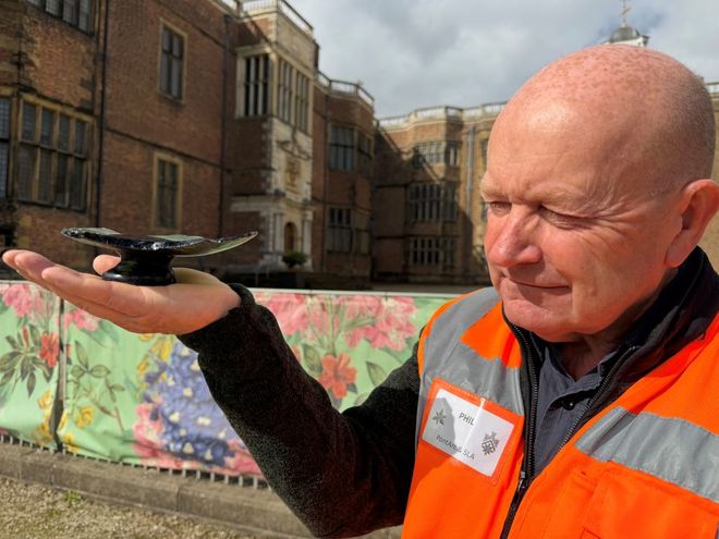 older man in high vis holding remains of a broken fruit bowl 