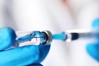 Nurse extracting vaccine with syringe from vial