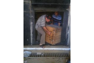 two men lifting wooden box out of a museum