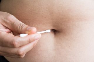 Person collecting a belly button sample with a cotton swab.