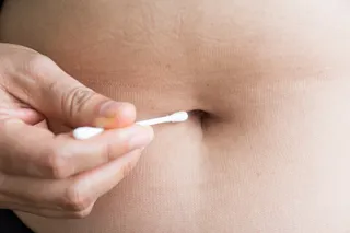 Person collecting a belly button sample with a cotton swab.