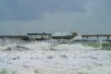 large waves crashing over a boardwalk 