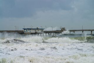 large waves crashing over a boardwalk 