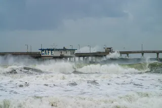 large waves crashing over a boardwalk 