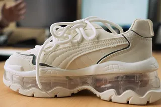 White smart shoe prototype with a thick, transparent sole, resting on a lab table.