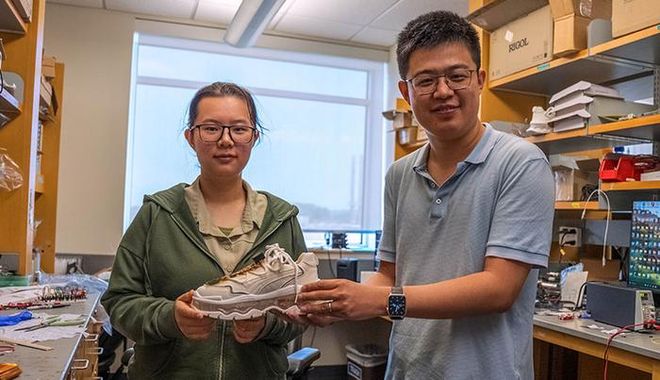 Fuying Dong (left) and Simiao Niu hold a white, footstep-powered smart shoe prototype in a Rutgers lab. Fuying Dong (left) and Simiao Niu hold a white, footstep-powered smart shoe prototype in a Rutgers lab.