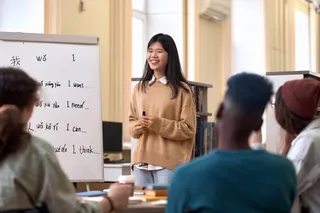 person teaching others a language with different languages written on a white board 