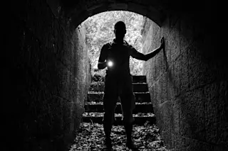 man in tunnel with flashlight